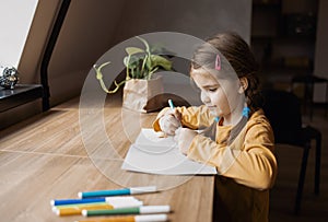 Cute brunette little girl drawing something in her notebook