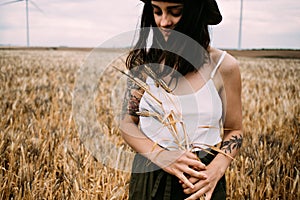 Cute brunette picks flowers in field of wheat