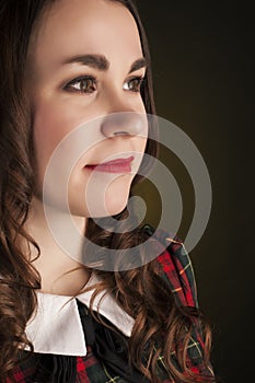 Cute brunette in tartan dress with red lips and curles. Studio portrait