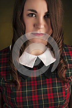 Cute brunette in tartan dress with red lips and curles. Studio portrait