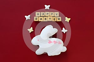 Cute bunny decorated with white and pink icing, HAPPY EASTER text made of wooden cubes and sugar butterflies