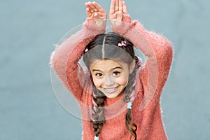 Cute bunny. Happy easter. Holiday bunny girl posing like rabbit grey background. Child smiling play bunny role. Playful