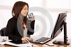 Cute business woman drinks cffee while working in office - cup o