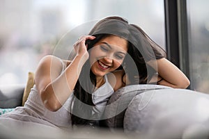 Cute casual lifestyle portrait of south asian indian woman laughing and smiling at home in city apartment