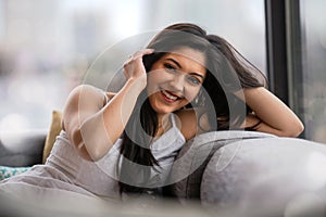 Cute casual lifestyle portrait of south asian indian woman laughing and smiling at home in city apartment