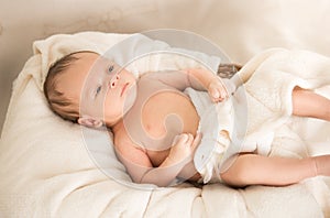 Cute caucasian baby boy lying under blanket on bed