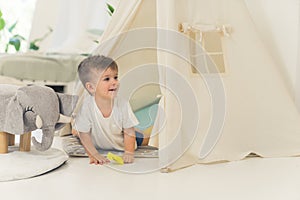 cute Caucasian baby boy playing in his tent in the living room, children concept