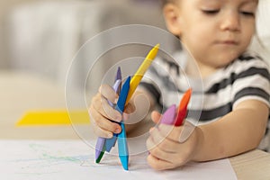 Cute caucasian baby girl drawing greeting card for mothers day. Image with selective focus on hand