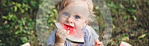 Cute Caucasian baby girl eating watermelon in park. Funny child kid sitting on ground with fresh fruit outdoors. Supplementary