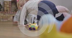 Cute Caucasian baby girl and her little sister crawling on the floor at home. Happy sisters having fun indoors. Leisure