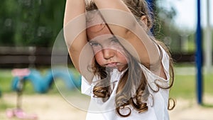 Cute caucasian baby, little girl crying on the playground in the park. Sad emotion of a child