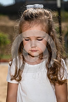 Cute caucasian baby, little girl crying on the playground in the park. Sad emotion of a child