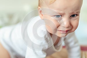 Cute caucasian blond toddler boy portrait crying at home during hysterics. Little child feeling sad. Little actor acting sadness