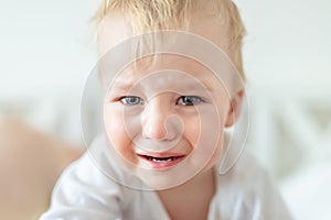 Cute caucasian blond toddler boy portrait crying at home during hysterics. Little child feeling sad. Little actor acting sadness