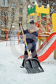 Cute caucasian boy with a big snow spade on playgrounutd in kindergarten