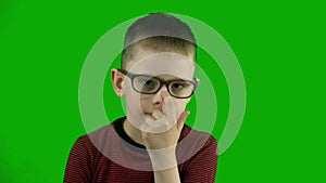 Cute Caucasian boy a preschooler with a thoughtful look adjusts his glasses on his nose and sincerely smiles.