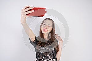 Cute caucasian friendly girl stands with a mobile phone in her hand and takes a happy emotional selfie on a white background in th