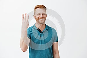 Cute caucasian friendly redhead man ordering three shots from bartender, smiling broadly showing number third and