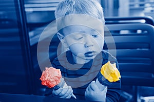 Cute Caucasian funny child boy holding two colorful red yellow ice cream in waffle cones. Kid trying to choose food. Puzzled,