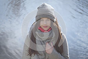 Cute Caucasian girl at the background of river or lake outdoors. Portrait of brunette beautiful woman looking at camera