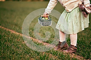 Cute caucasian pre-schooler blonde girl at Easter egg hunt by grandma& x27;s country house, outdoor