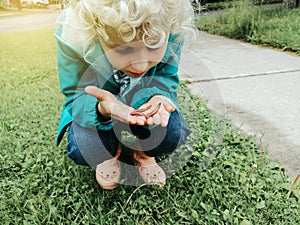 Cute Caucasian preschool girl holding rain worm in hands. Child kid learning studying nature around. Natural biology science.