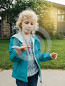 Cute Caucasian preschool girl holding rain worm in hands. Child kid learning studying nature around. Natural biology science.