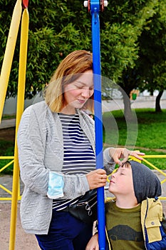 cute charming boy of five years old, swinging on an outdoor playground. Communication between mother and son on the