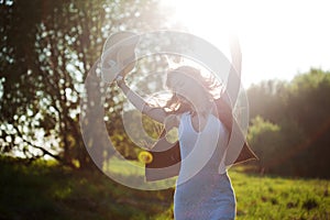 Cute charming girl in summer in the field. Young woman is happy and feels free outdoors.