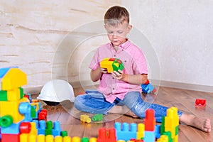 Cute cheeky young boy playing with building blocks