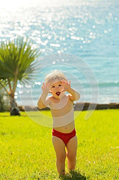 Cute cheerful baby boy makes frightening attacking gesture