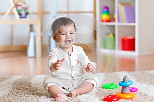 Cute cheerful baby playing with colorful toy at home