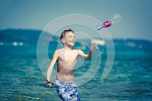 Cute cheerful child in swimware playing in sea with toy