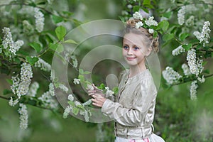 Cute cheerful girl in the flowered cherry-tree garden