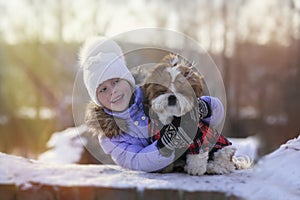 Cute cheerful girl hugs her puppy on walk winter day