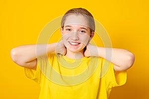 Cute cheerful girl. Studio portrait of a smiling teenage girl on a yellow background