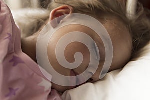 Cute cheerful little 3-4 years preschool baby girl kid sleeping sweetly in white crib during lunch rest time in pink