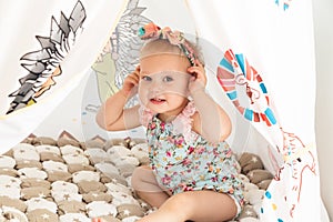 Cute cheerful little girl is playing in colorful tent