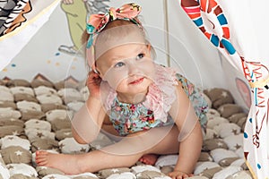 Cute cheerful little girl is playing in colorful tent