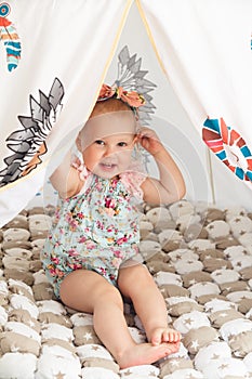 Cute cheerful little girl is playing in colorful tent