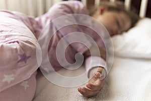 Cute cheerful little 3-4 years preschool baby girl kid sleeping sweetly in white crib during lunch rest time in pink