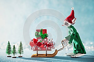 Cute Cheerful Santas Helper Elf Loading Christmas Gifts Onto Santas Sleigh. North Pole Christmas Scene. Elf at work.