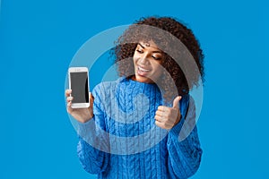 Cute and cheerful, satisfied african-american woman showing something on display, make thumb-up gesture, looking