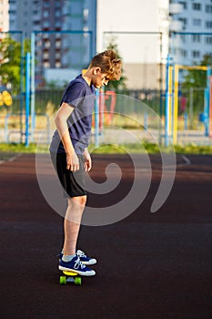 Cute cheerful smiling Boy in blue t shirt sneakers riding on yellow skateboard. Active urban lifestyle of youth, training, hobby