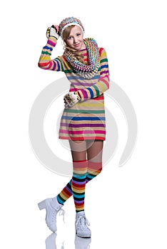 Cute cheerful teenage girl wearing colorful striped sweater, scarf, gloves, hat and white boots isolated. Winter clothes.