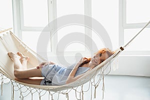 Cute cheerful young redhead lady lies on hammock