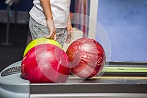 Cute child with ball in bowling club. Kid is playing bowling