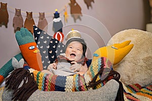 Cute child in a basket with toys, adorned with a crown