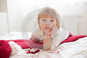 Cute child, blond boy, playing with white and red bracelet