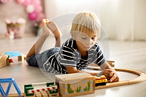 Cute child, blond toddler boy, playing with trains at home